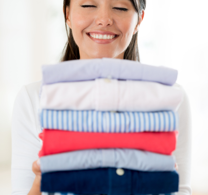 Woman holding neatly folded laundry, fresh and clean linens for Sprinkle Laundry service.
